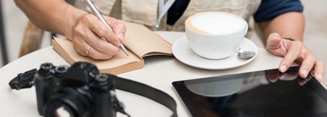 Professional writer crafting custom essays at desk with laptop and notepad, demonstrating expert journalistic approach to academic writing services